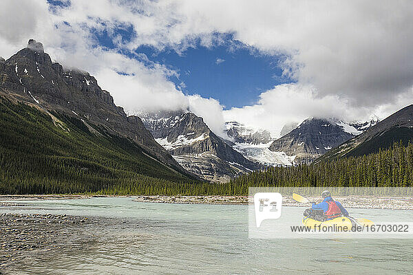 Forscher paddelt auf einem gelben Floß in Richtung der Rocky Mountains  Banff.