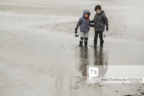 Zwei Jungen paddeln an einem kalten Tag am Strand