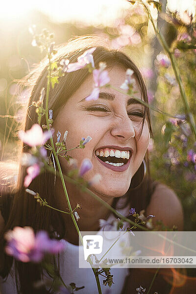 Porträt des jungen Mädchens lachend unter den lila Blumen in der Natur