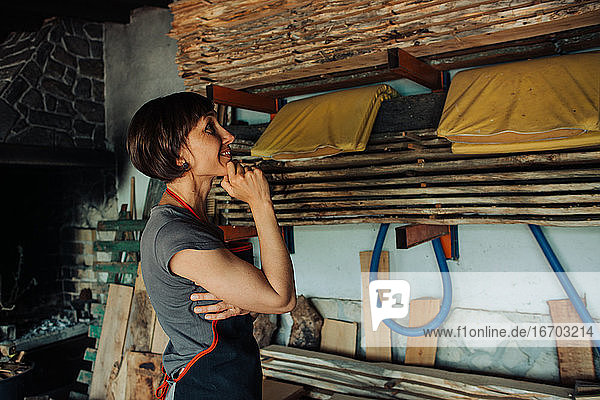 Handwerkerin in einer Schreinerei bei der Betrachtung von gesägtem Holz