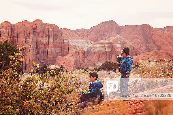 Two Boys playing on trail by the red sandstone cliffs and mountains