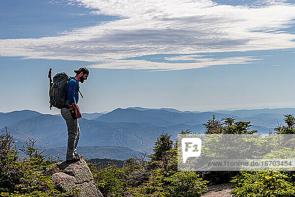 Mann steht auf dem Gipfel eines Berges und blickt auf die Weißen Berge hinunter.
