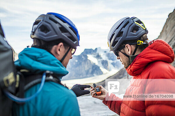 Zwei Bergsteiger benutzen ein GPS  um sich im Gebirge zurechtzufinden.
