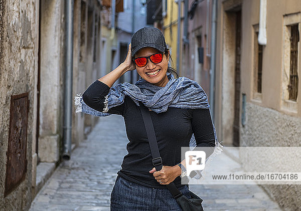 woman wearing baseball cap and orange sunglasses in street alley