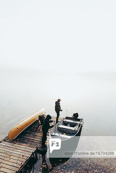 Mann und Kind machen sich an einem nebligen Tag in einem Boot zum Fischen bereit.