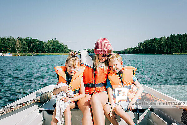 Mutter saß auf einem Boot und umarmte ihre Kinder glücklich im Sommer in Schweden
