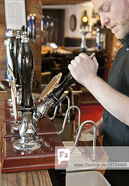 bartender pulling beer at British pub
