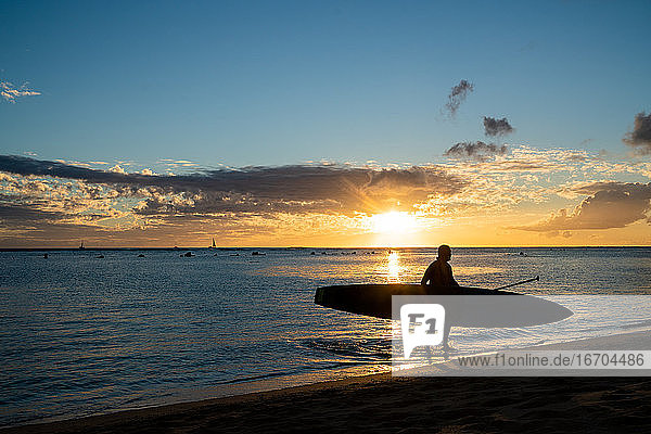 Stand up Paddler geht aus hawaii Ozean bei Sonnenuntergang