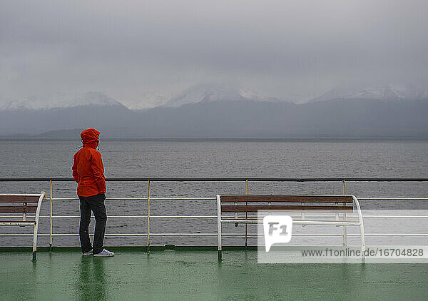 Frau blickt von einem Passagierschiff in Patagonien auf eine düstere Szenerie