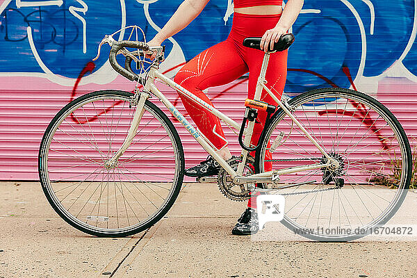 Junge Sportlerin mit Fahrrad im Freien auf einer Straße in Brooklyn.
