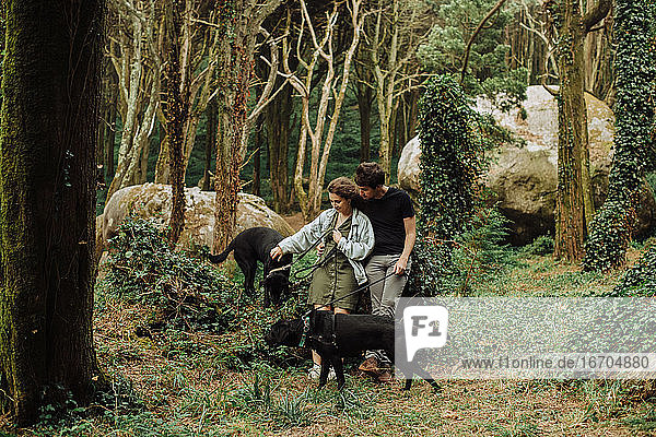 Millennial man and woman with dogs on a leash in the natural park