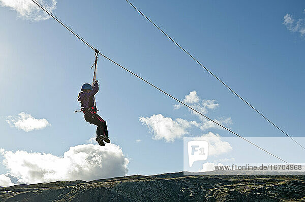 girl going down on a zip line at high rope access course in Iceland