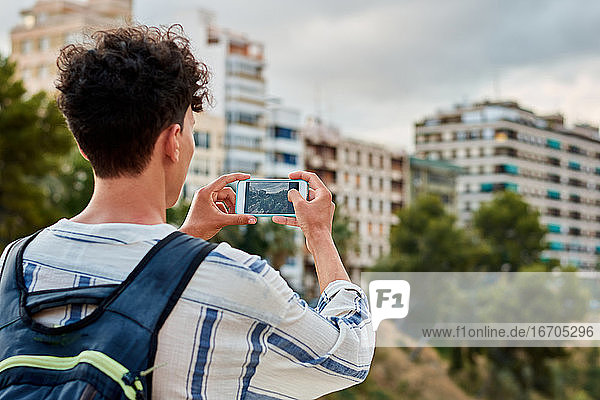 Close-up of a young afro-haired man is taking a photo with his mobile