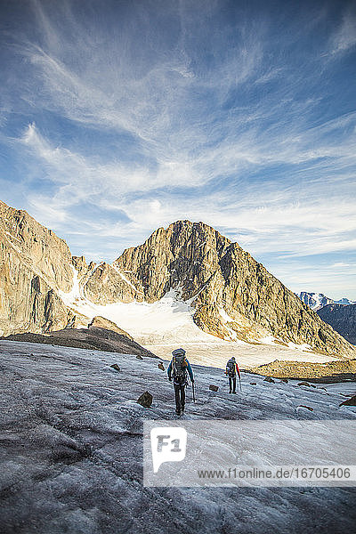 Zwei Männer überqueren einen Gletscher über einen hohen Bergpass.