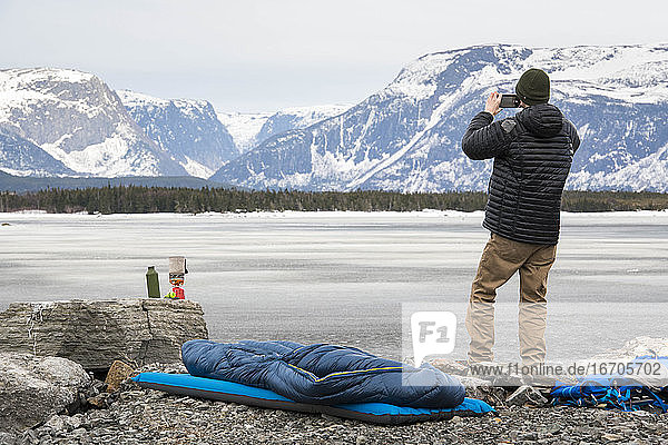Rückansicht eines männlichen Wanderers  der mit seinem Smartphone Berge fotografiert