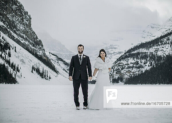 Ein frisch verheiratetes Paar steht auf dem zugefrorenen Lake Louise  Alberta  Kanada  im Winter