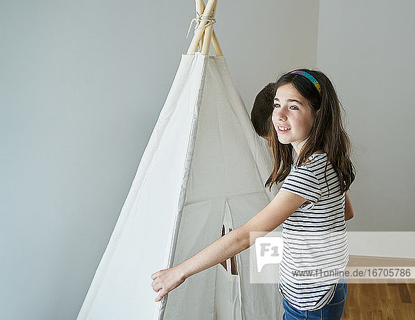 Kinder legen die Stöcke  um ein Tipi-Zelt in ihrem Haus zu bauen. Kreativitätskonzept