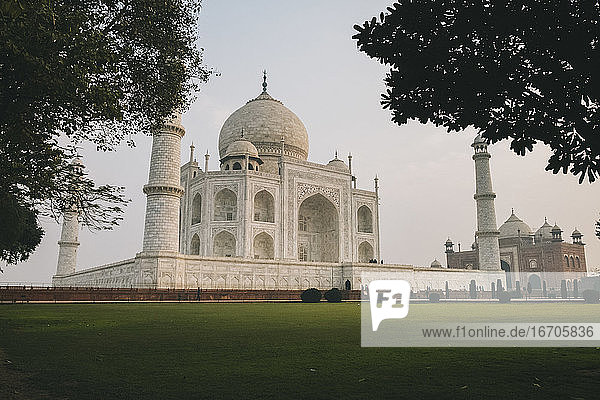 Taj Mahal umgeben von Bäumen in den symmetrischen Gärten rund um den Komplex bei Sonnenaufgang  Agra  Indien