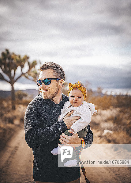 A man with a baby is standing in a desert of California