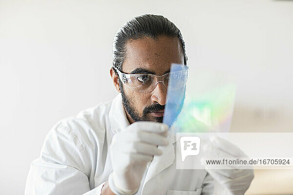 junger Mann  Wissenschaftler mit Laborkittel  der eine Probe kontrolliert
