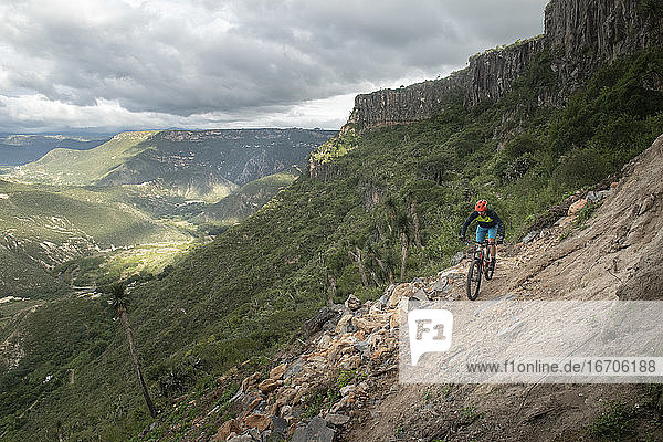 One man riding a bike on a narrow trail at a canyon in Peña del Aire