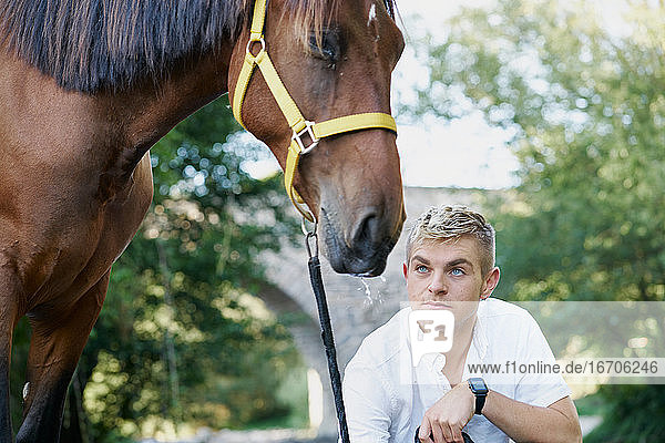 Porträt eines blonden jungen Mannes mit einem Pferd