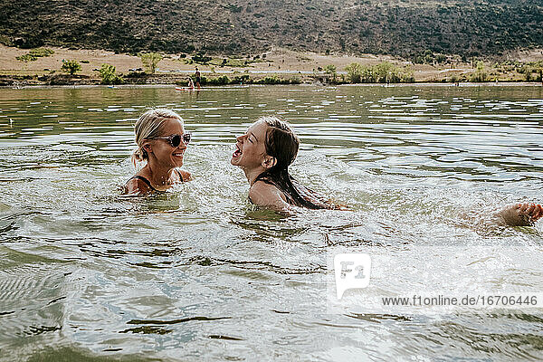 Glückliche Mutter und Tochter schwimmen an einem Sommertag in einem See