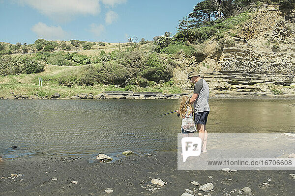 Vater und Tochter beim Angeln an einem malerischen Flussabschnitt