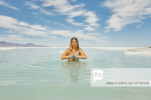 Junge Frau meditiert im Wasser in den Bonneville Salt Flats.