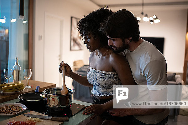 Mann hilft schwarzer Freundin bei der Zubereitung des Abendessens