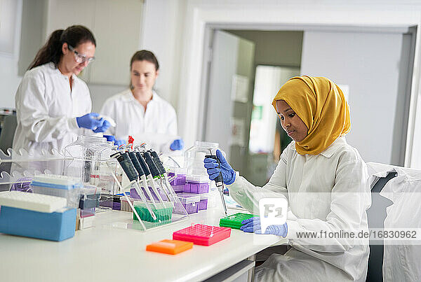 Weibliche Wissenschaftlerin im Hijab füllt Pipettenschalen im Labor