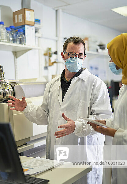 Wissenschaftler mit Gesichtsmasken sprechen im Labor
