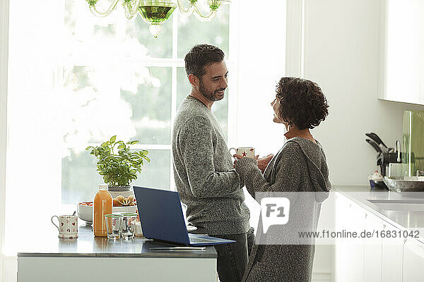 Happy couple talking and working in morning kitchen