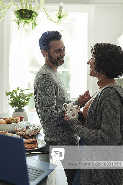 Glückliches Paar im Gespräch und Kaffee trinken in der Küche am Morgen