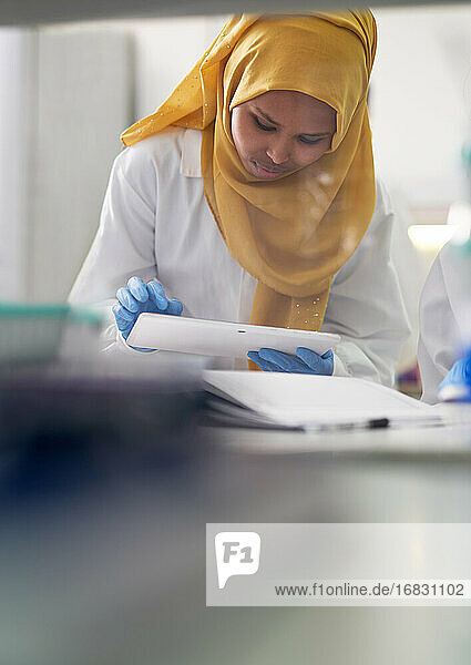 Weibliche Wissenschaftlerin im Hijab mit digitalem Tablet im Labor