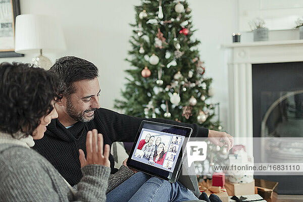 Glückliches Paar Video-Chat mit Familie auf digitalen Tablette an Weihnachten