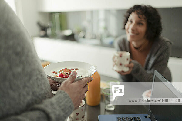 Paar essen Frühstück und sprechen in der Morgen Küche mit Laptop
