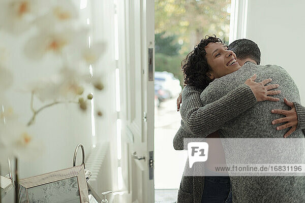 Glücklich liebevolles Paar umarmt an der Haustür des Hauses