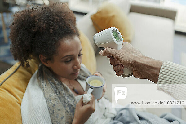 Ehemann nimmt Temperatur der kranken Frau mit Infrarot-Thermometer