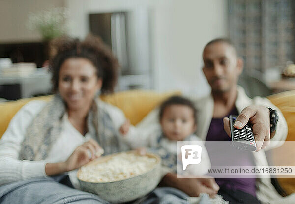 Familie mit Fernbedienung beim Fernsehen mit Popcorn auf dem Sofa