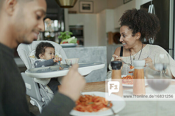 Glückliche Eltern und Baby Tochter essen Spaghetti am Esstisch