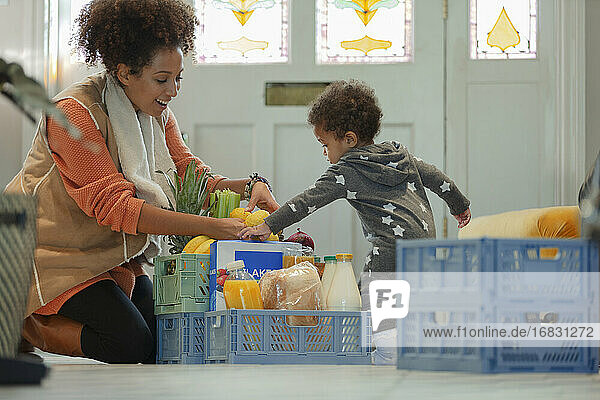 Baby-Tochter hilft Mutter beim Ausladen der Lebensmittellieferung