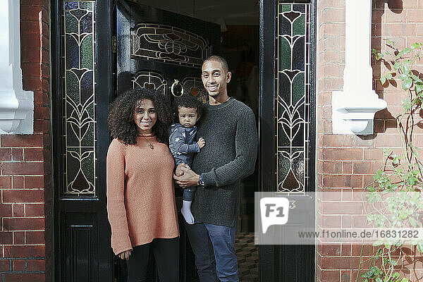 Porträt glückliche Eltern mit Baby Tochter an der Haustür von Haus