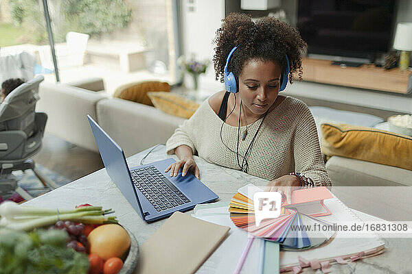 Weiblicher Designer mit Farbmustern  der von zu Hause aus am Laptop arbeitet