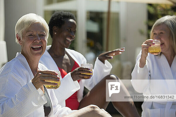 Glückliche ältere Frau genießt Cocktail mit Freunden auf der sonnigen Hotelterrasse