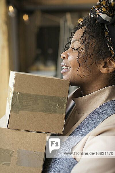 Glückliche weibliche Ladenbesitzerin trägt Stapel von Kisten