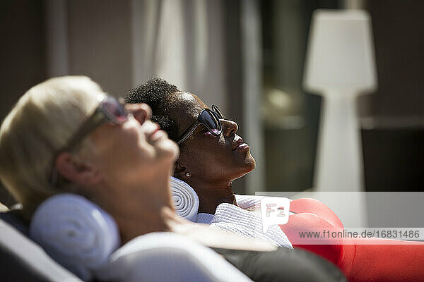 Serene ältere Frauen Freunde Sonnenbaden in Sonnenbrille auf sonnigen Terrasse