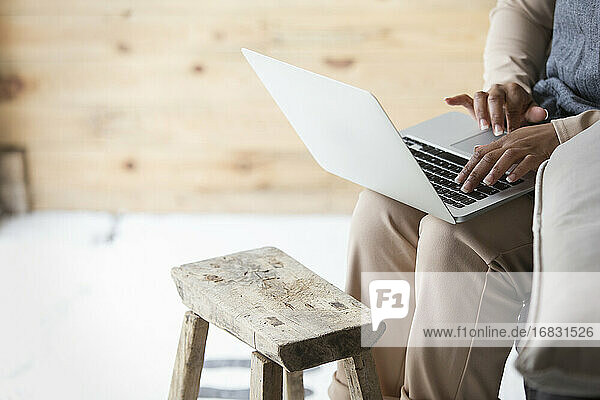 Weibliche Ladenbesitzerin mit Laptop am Holzschemel