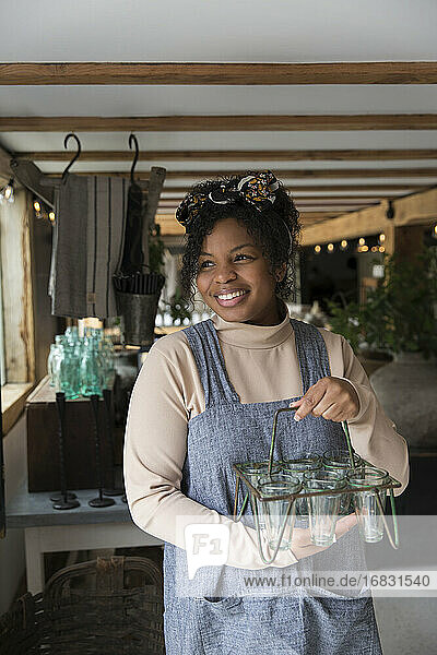 Porträt glückliche weibliche Ladenbesitzerin hält Glas Pflanzenhalter
