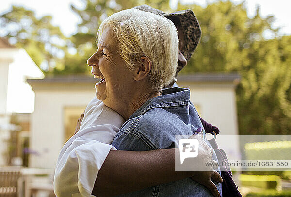 Glückliche ältere Frauen Freunde umarmen auf der Terrasse